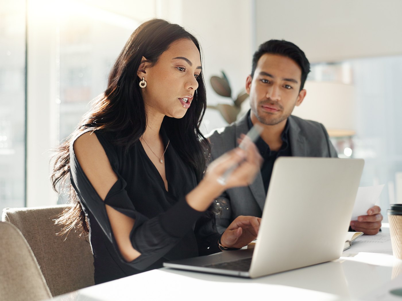 Two colleagues reviewing loan documents at a laptop